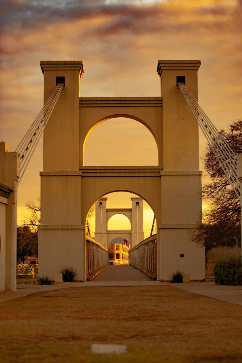 The Waco suspension bridge in the heart of Texas illuminated by the golden sun.  Photo by David Holifield - Unsplash.